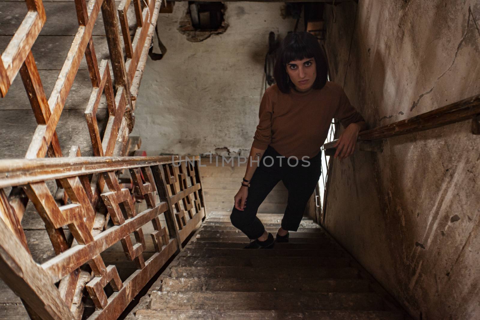 Portrait of a brunette girl in a staircase of an abandoned House, image in low light