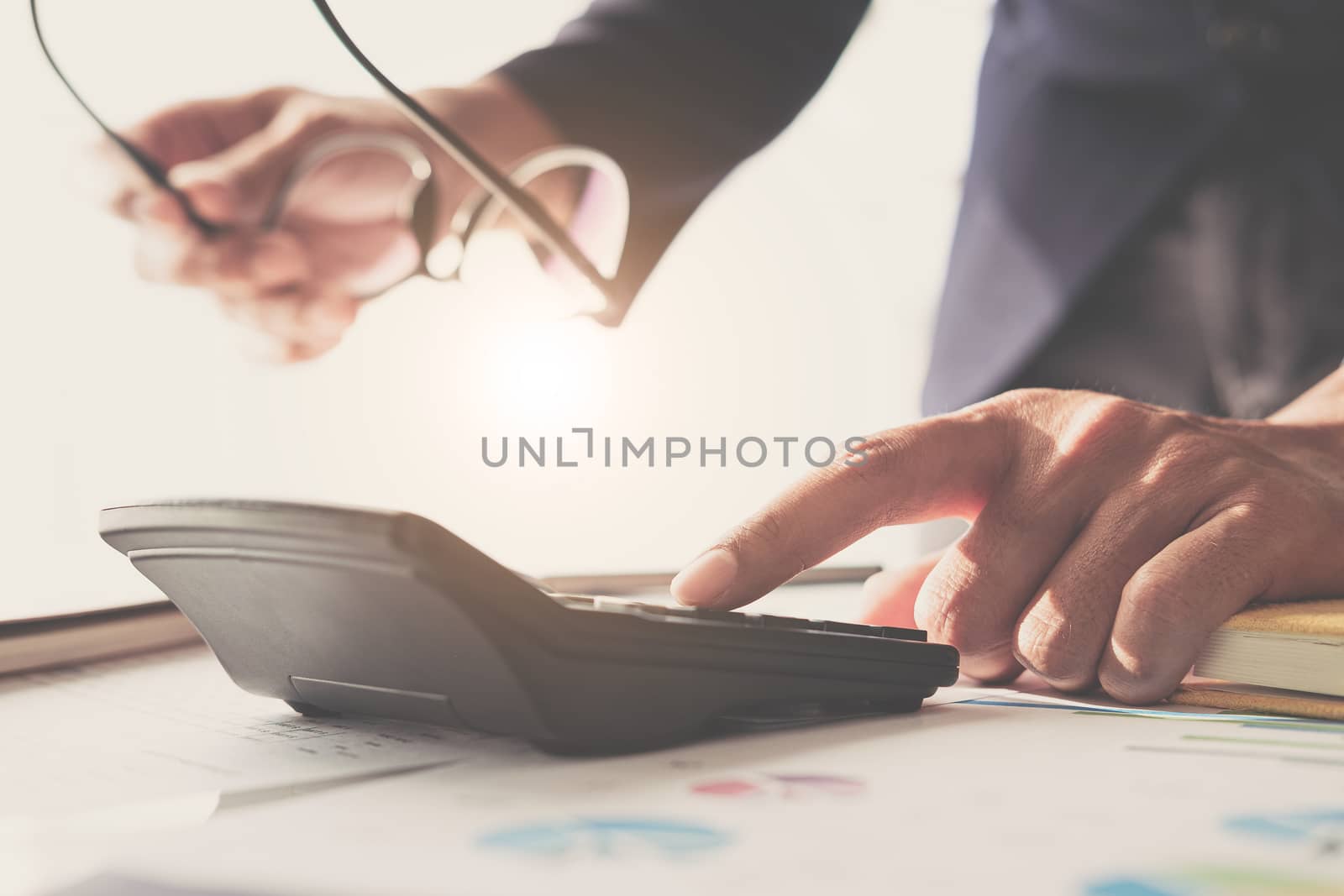 Close up of businessman or accountant hand holding glasses worki by wichayada