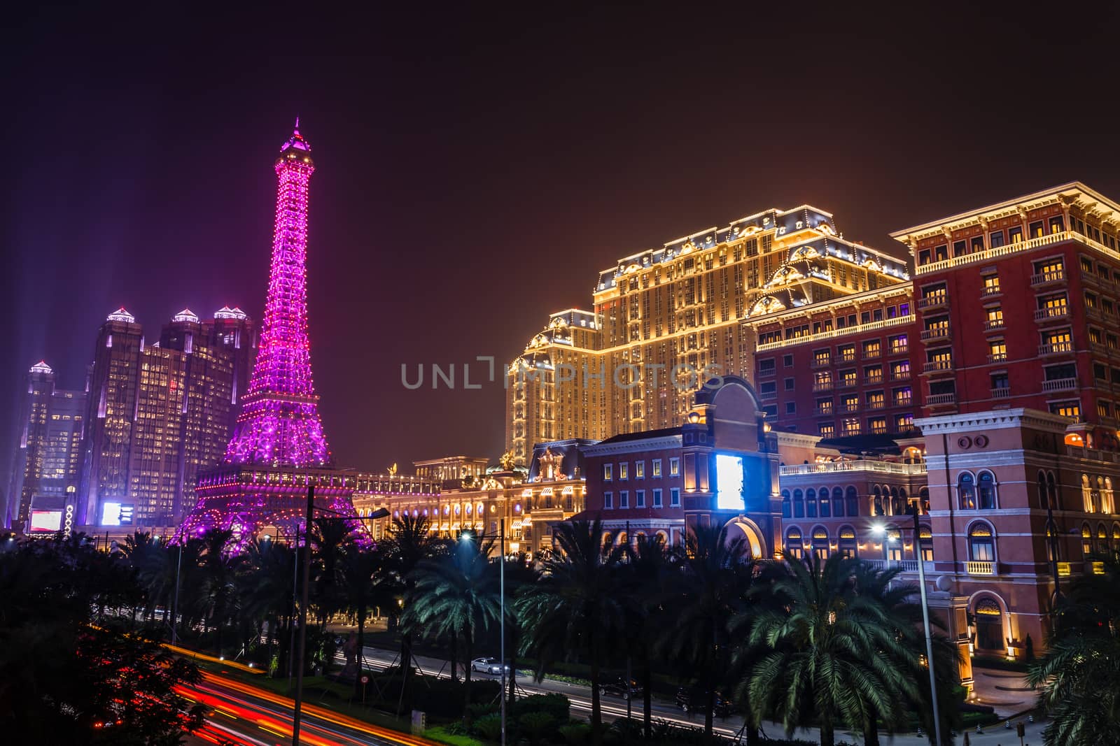 Street with palms full of neon lights of Macau skyscrapers and luxury casinos, Macau