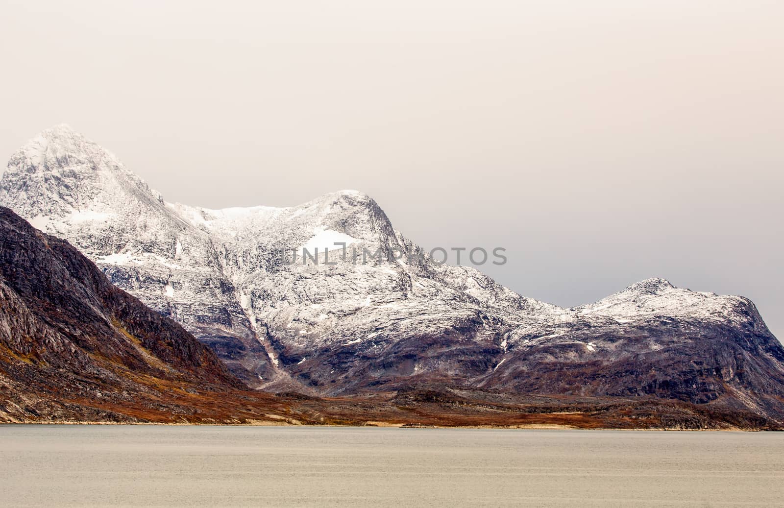 Snow topped mountains with Ukkusissat Little Malene peak and sea by ambeon