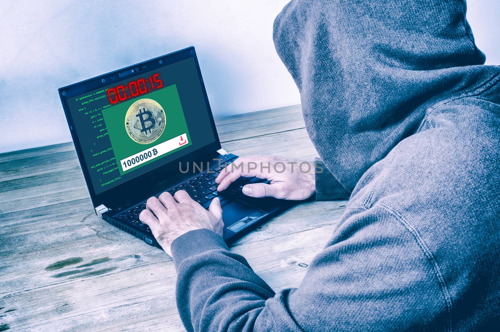 Back view of a hacker wearing a hoodie and stealing bitcoins on  by mbruxelle