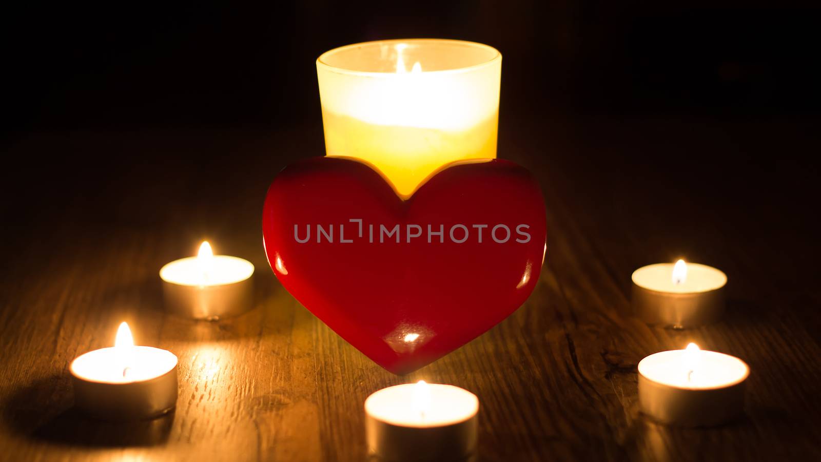 Christmas divination. Fortune telling. Divination for love. The red heart stands in the middle of the lighted candles. Ritual of love spell of the person. Postcard for Valentine's day or women's day