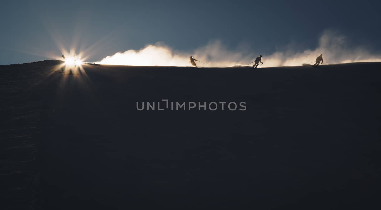 Skiers enjoying an early morning in slopes at the Austrian Alps with a nice sunshine backlight