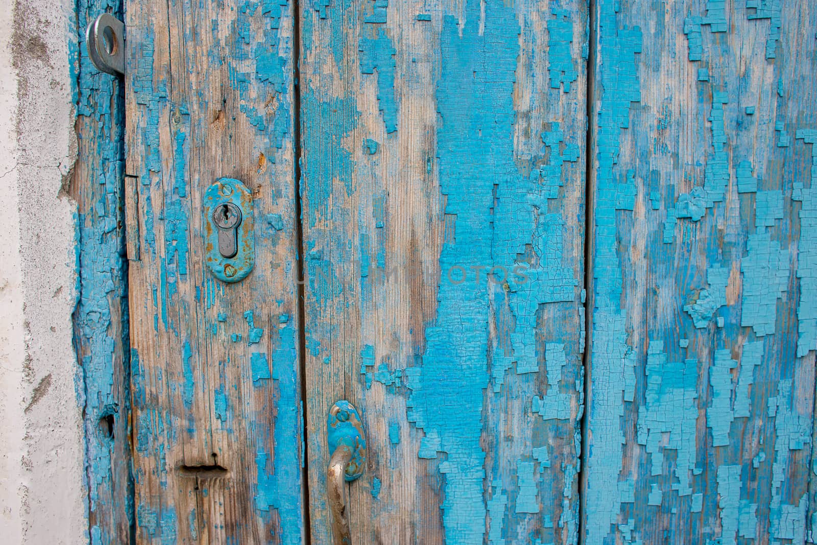 Background from an old wooden door painted in blue. Texture of peeling paint on the boards