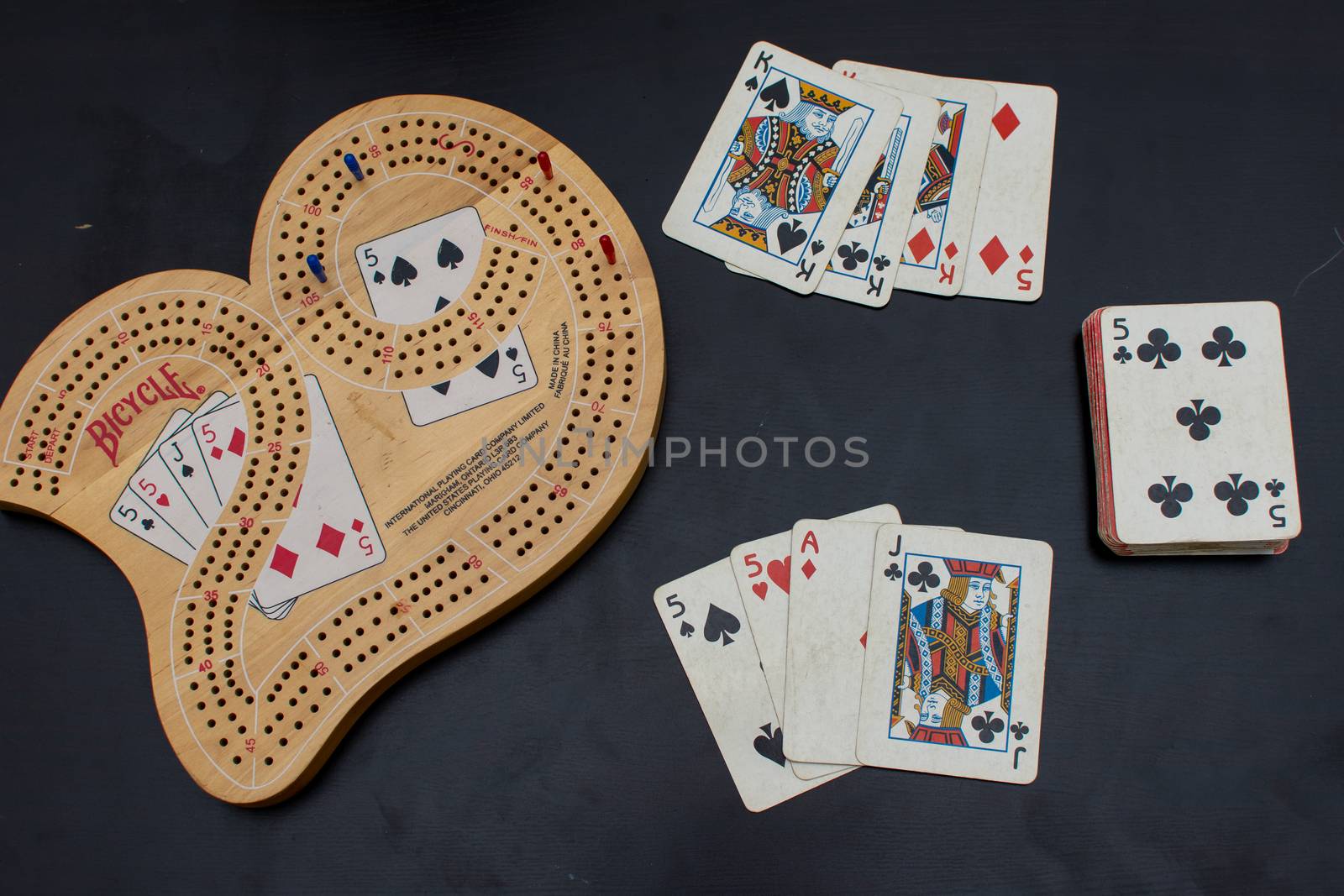 RAK, RAK/UAE - 4/20/2019: "Top view of a Cribbage card game and board up close looking at the blue and red pegs with an excellent best card hand of 29 points, fives and a jack."