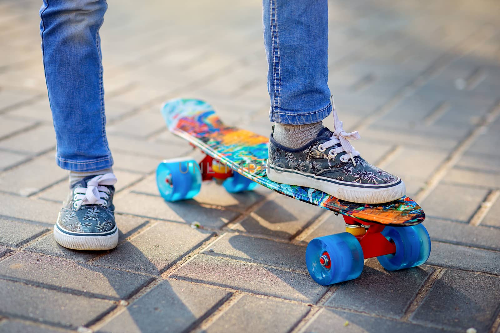 Children's feet in sneakers close-up on a skateboard. Children play sports. Physical development of children.