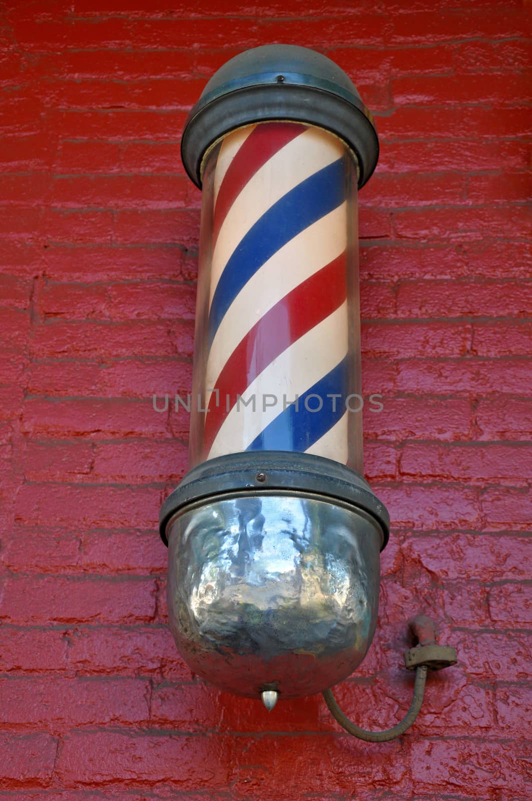 Old striped barbershop pole on red brick wall