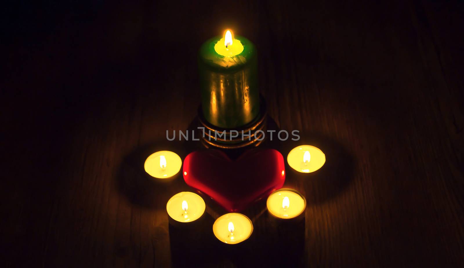 A red heart lies between the candles on a wooden table. gifts for Valentine's Day. mother's day greeting card. International women's day Red heart  gift card for a loved one, a Declaration of love.