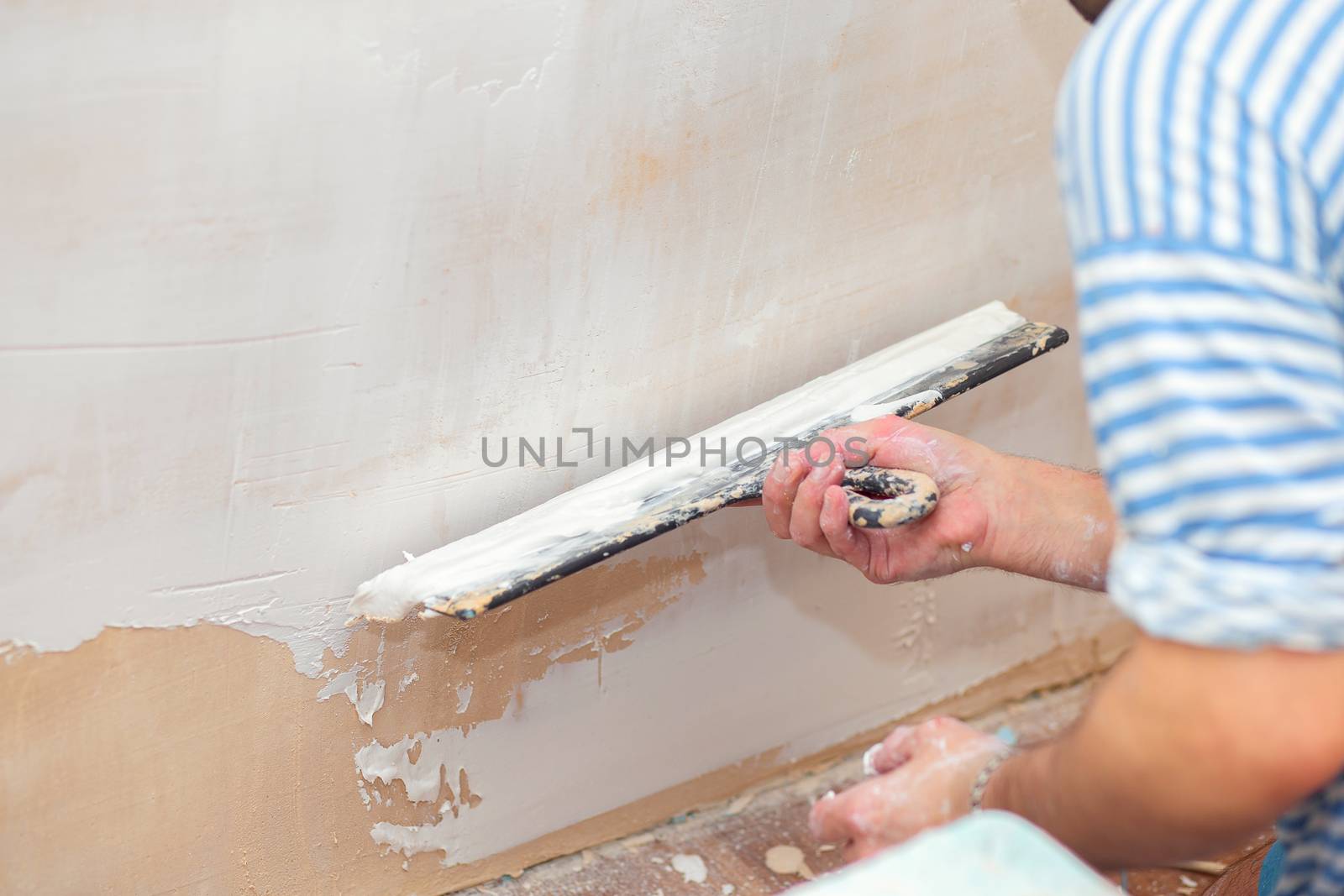 Repair of the living quarters. Putty interior walls with a wide metal spatula
