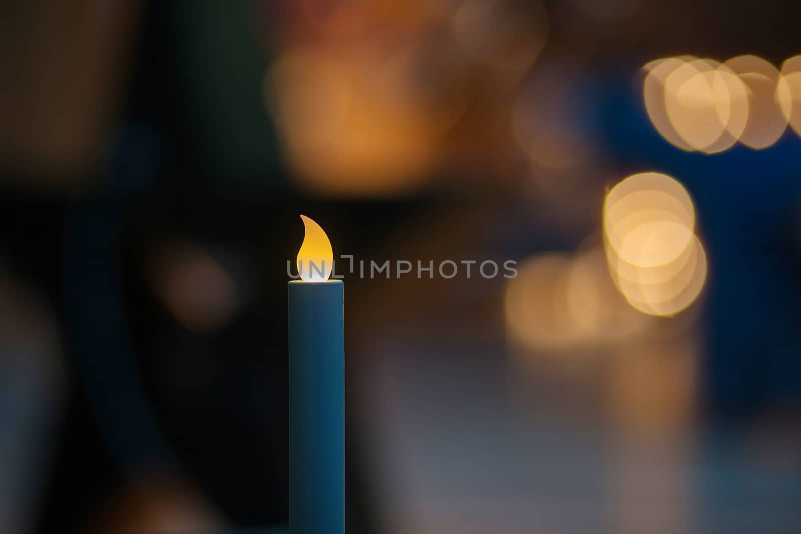 The bulb in the form of a candle shines in the dark. Decoration of an interior artificial candles. Bokeh