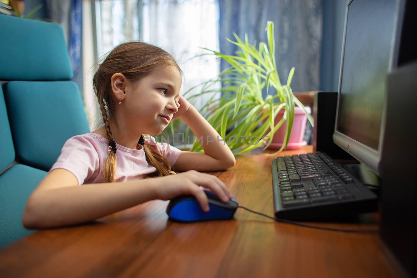 Tired girl schoolgirl is engaged at home on the computer. A child in distance learning. Computer games