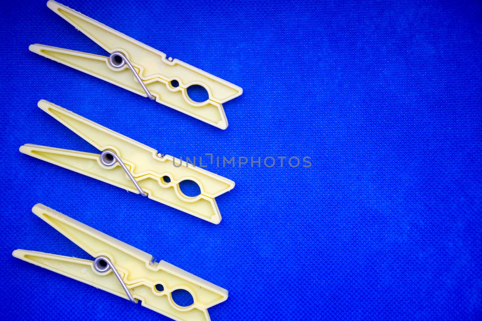 Yellow clothes pins on blue background concept (left side). Open by kingmaphotos