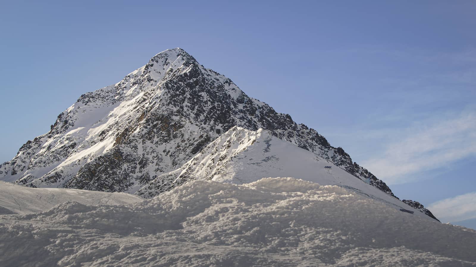 Blue skies in a sunny day with a mountain peak at the Austrian Alps during winter