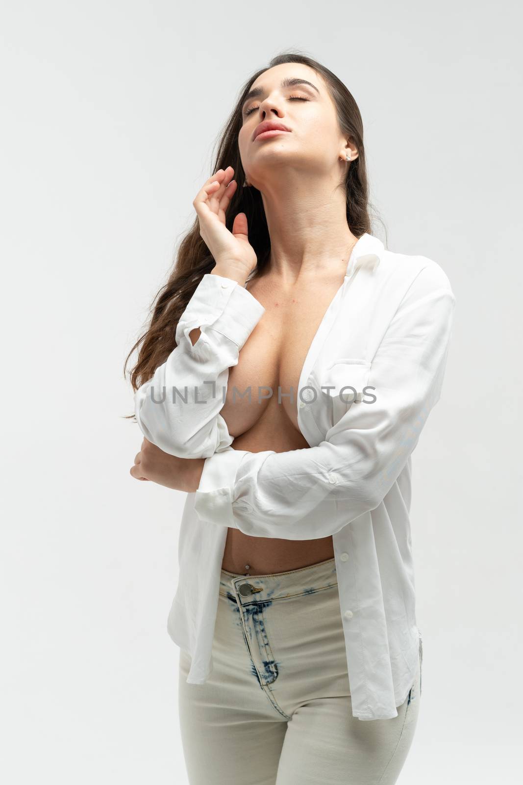 young beautiful girl pose in a white shirt and white jeans in the studio