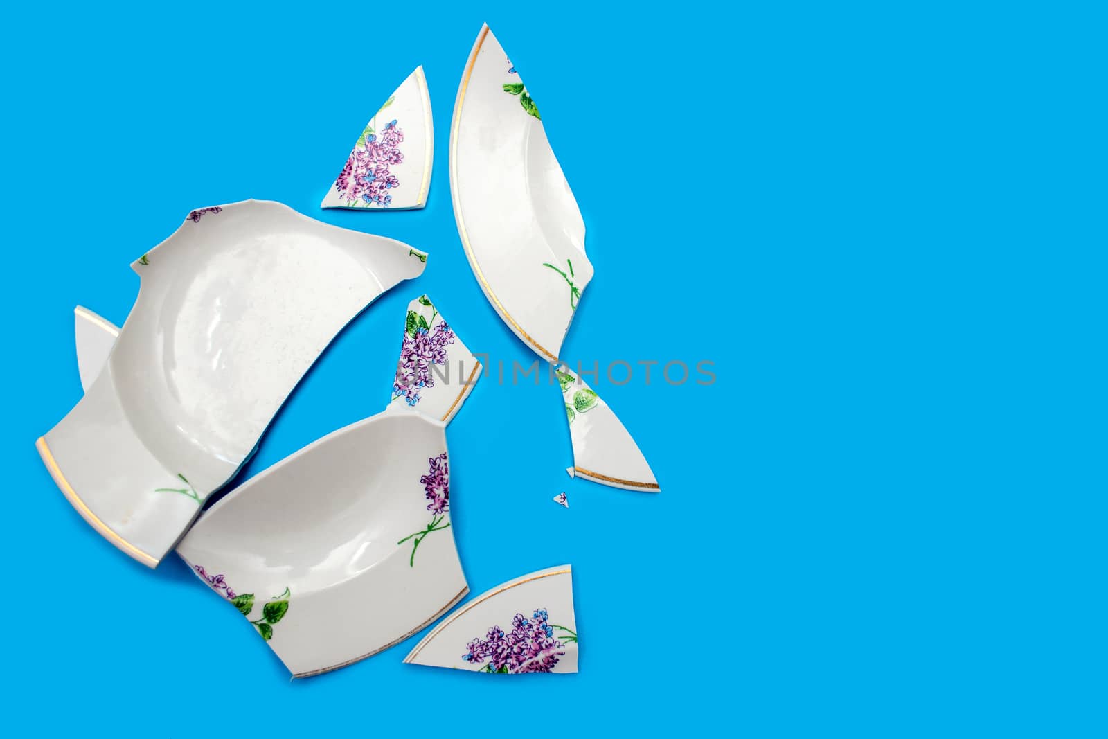 Shards of a broken plate on a blue background. Small pieces of chopped dishes.