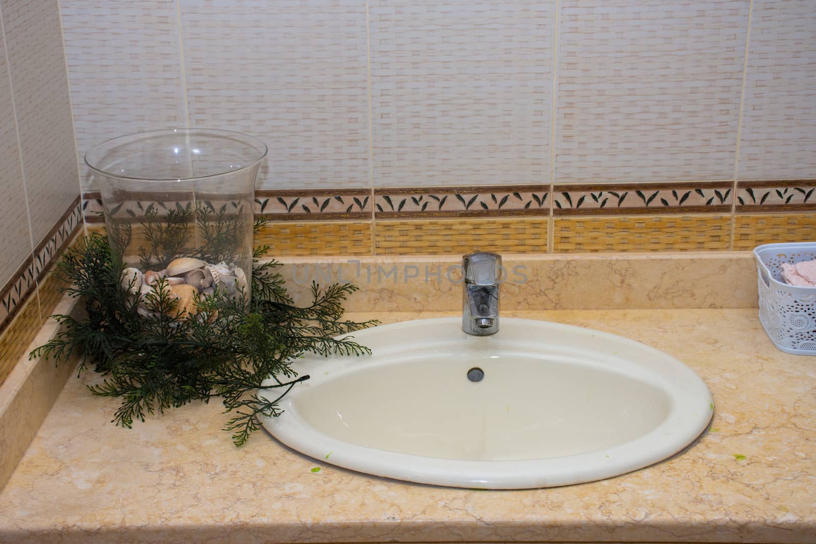 Open bathroom sink in house with tile, and bowl of shells with g by kingmaphotos