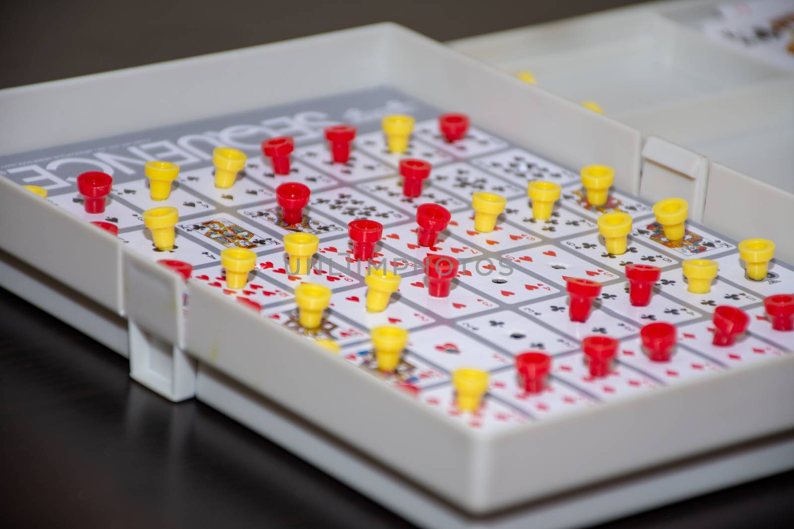 "RAK, RAK/UAE - 5/18/2019: Family fun card sequence game showing the board game with yellow and red pegs creating a sequence or row of five."