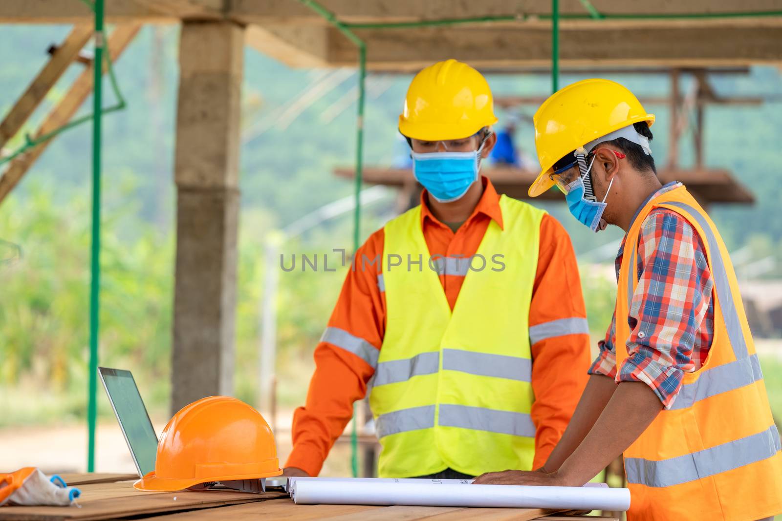 Group of Asian engineers wearing protective mask to Protect Against Covid-19 with helmet safety in the construction site,Coronavirus has turned into a global emergency,Safety concept.