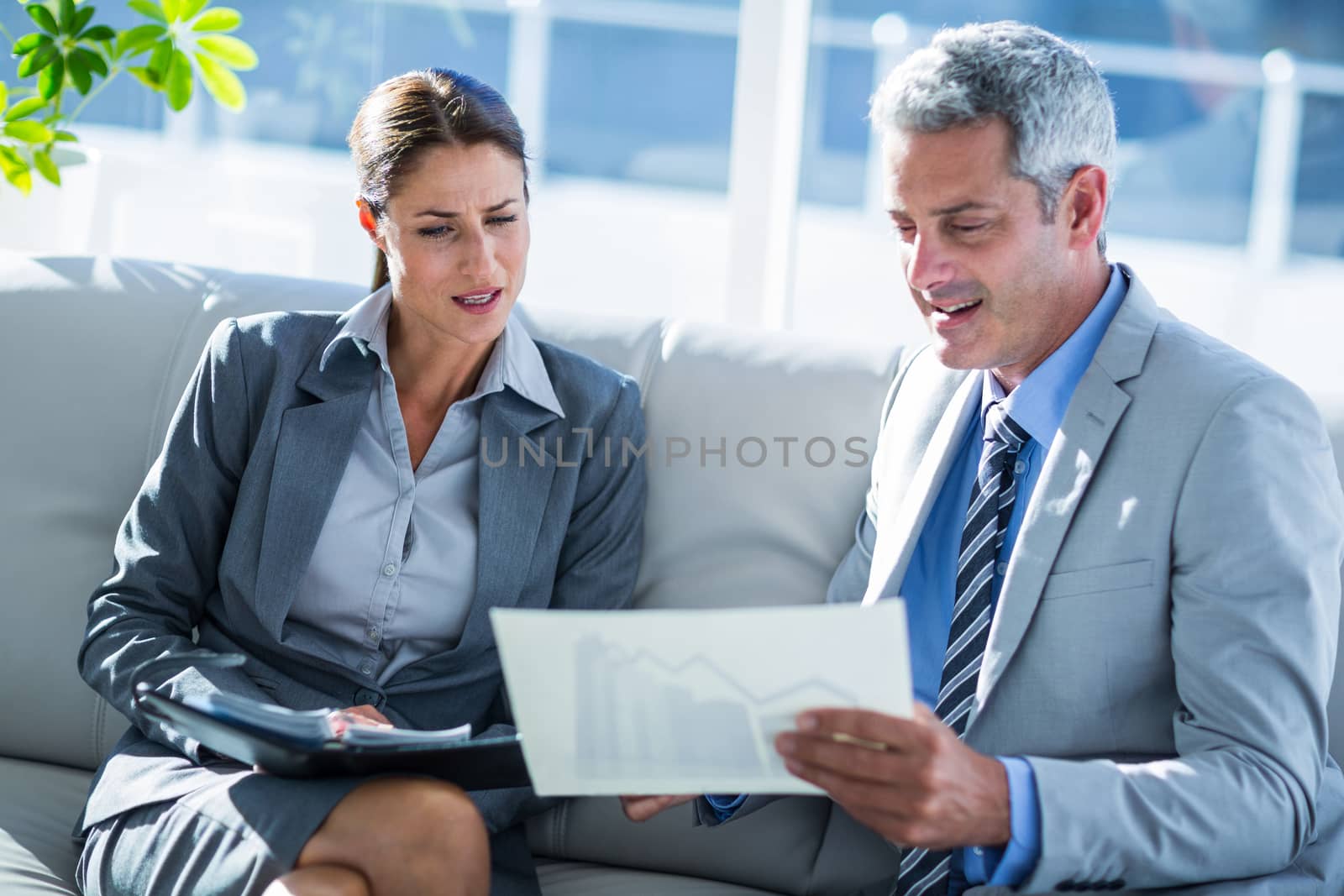 Business people looking at graphic on paper in office 