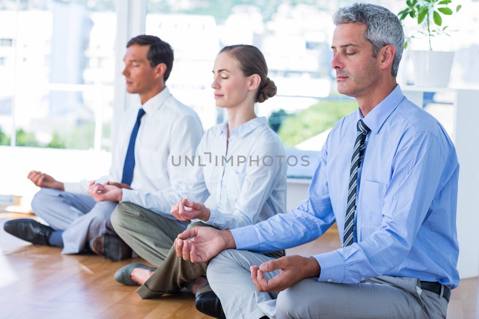 Business people doing yoga on floor in office