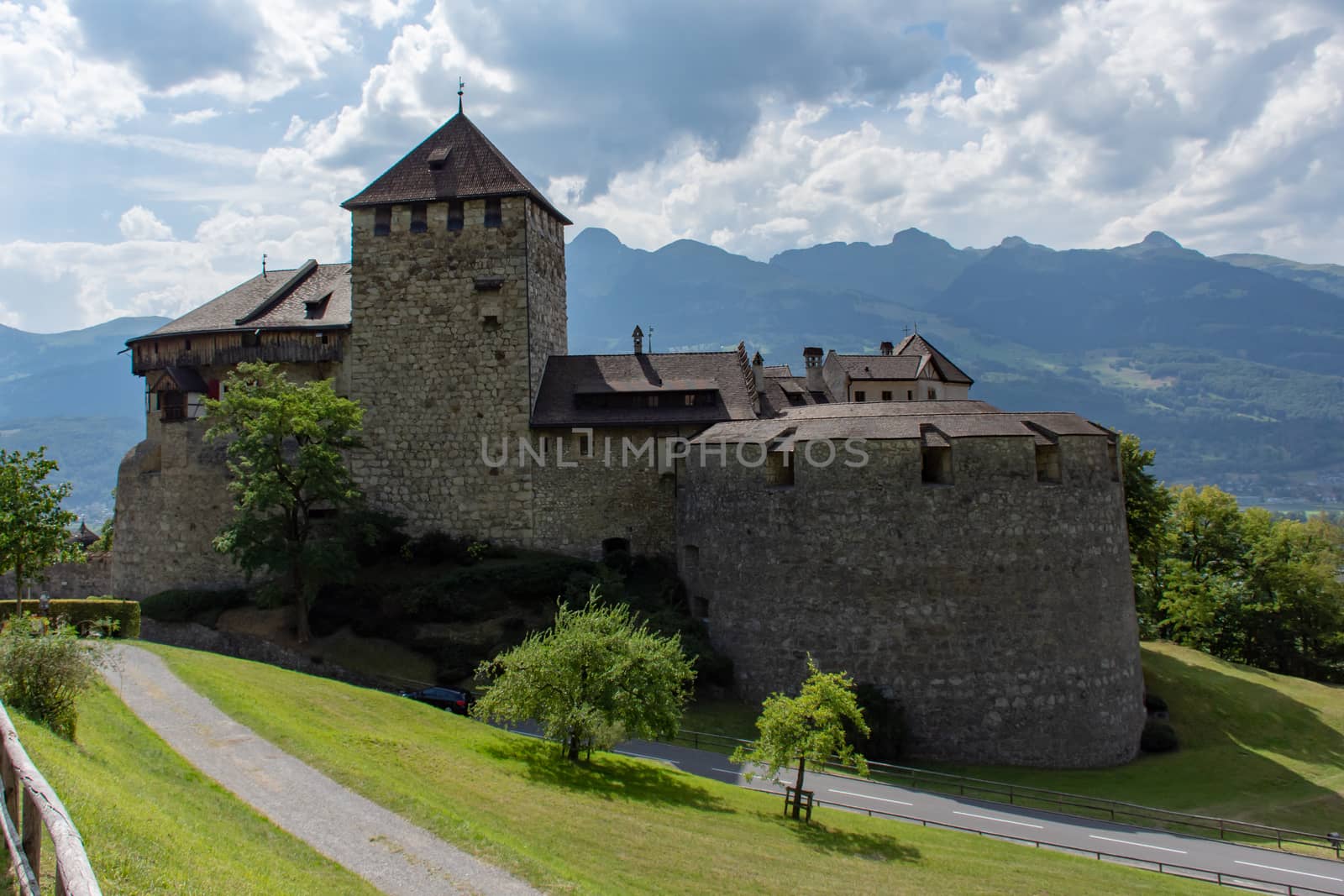 Vaduz Castle in Liectenstein close up with clouds, mountains and grass in background.