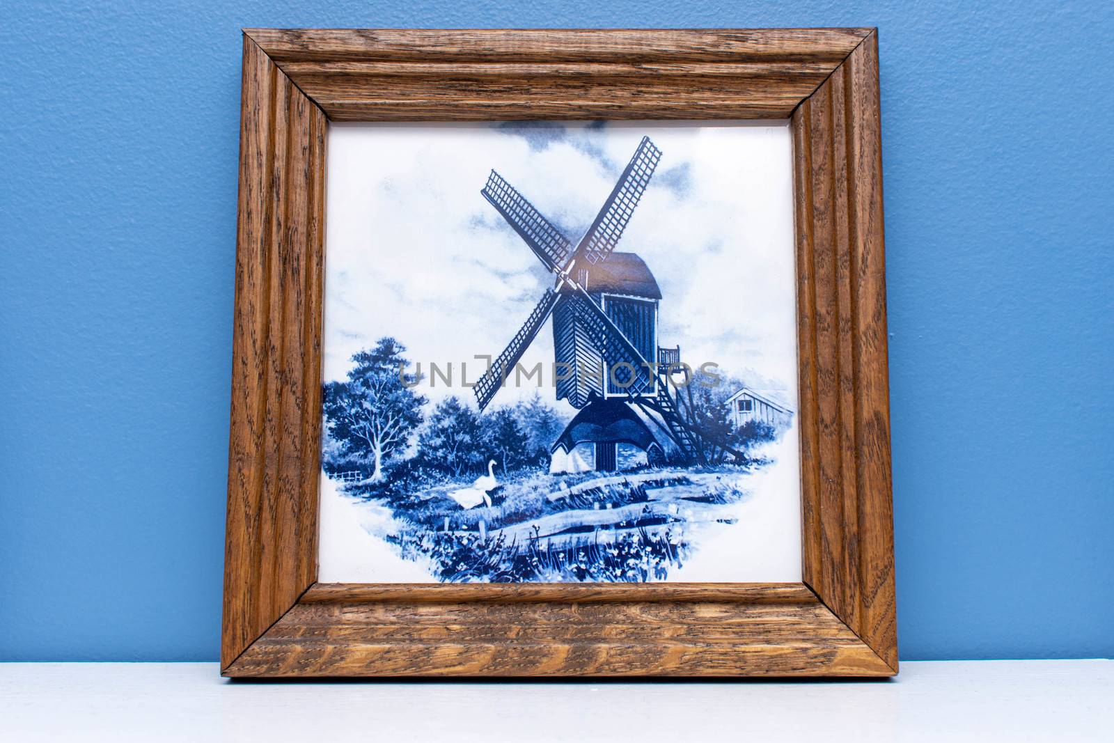 Delft Blue tile in a frame, a souvenir from Holland/Netherlands. hanging on a wall making a windmill and typical farm scene.