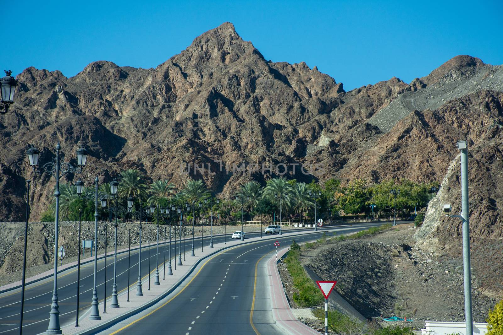 "Muscat, Muscat/Oman - 12/17/2019: Mountain highway road with rocky mountains and blue sky in Muscat, Oman near Muttrah Souq and Old Town. "