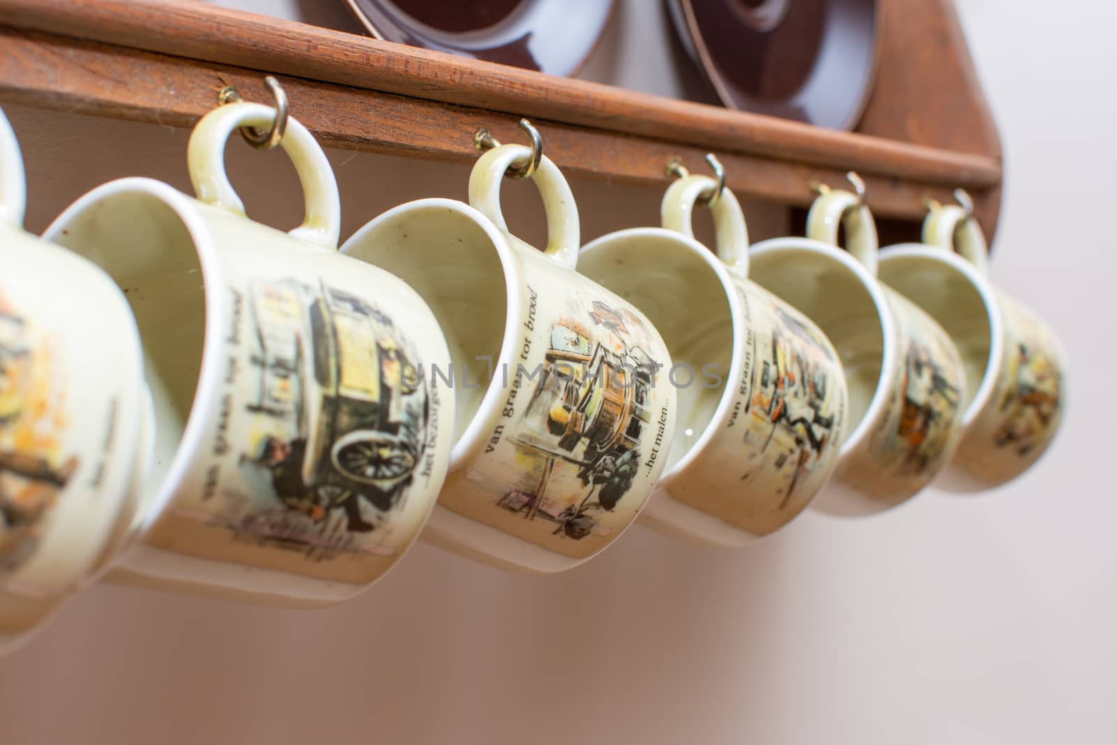Dutch mugs and plates hanging on a rustic wooden frame on the wall. Culture of Holland in the Netherlands. Common in homes.