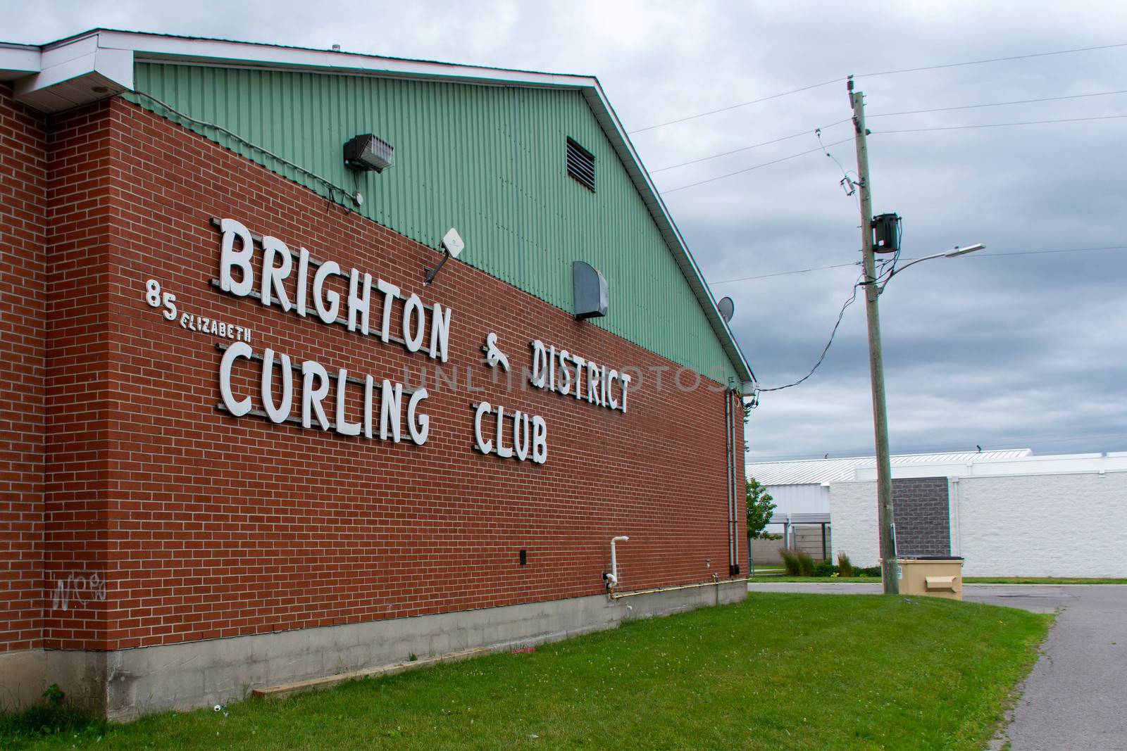 "Brighton, Ontario/Canada - 07/22/2019: Downtown rural sreet of small town Canadian city of Brighton near Pesquile Lake Provincial Park curling club sign and arena."