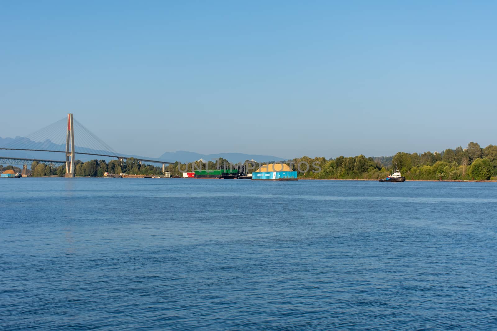 "New Westminster, BC/Canada - 8/3/2019: A Tugboat pulling a Ledcor Group barge in New Westminster, British Columbia, Canada looking from the Quay in the Fraser River, Skytrain Bridge into Surrey."