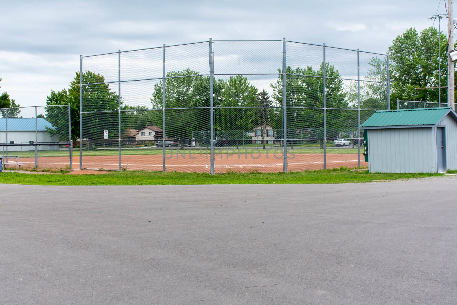 Baseball or softball diamond through a fence in  park in a small by kingmaphotos