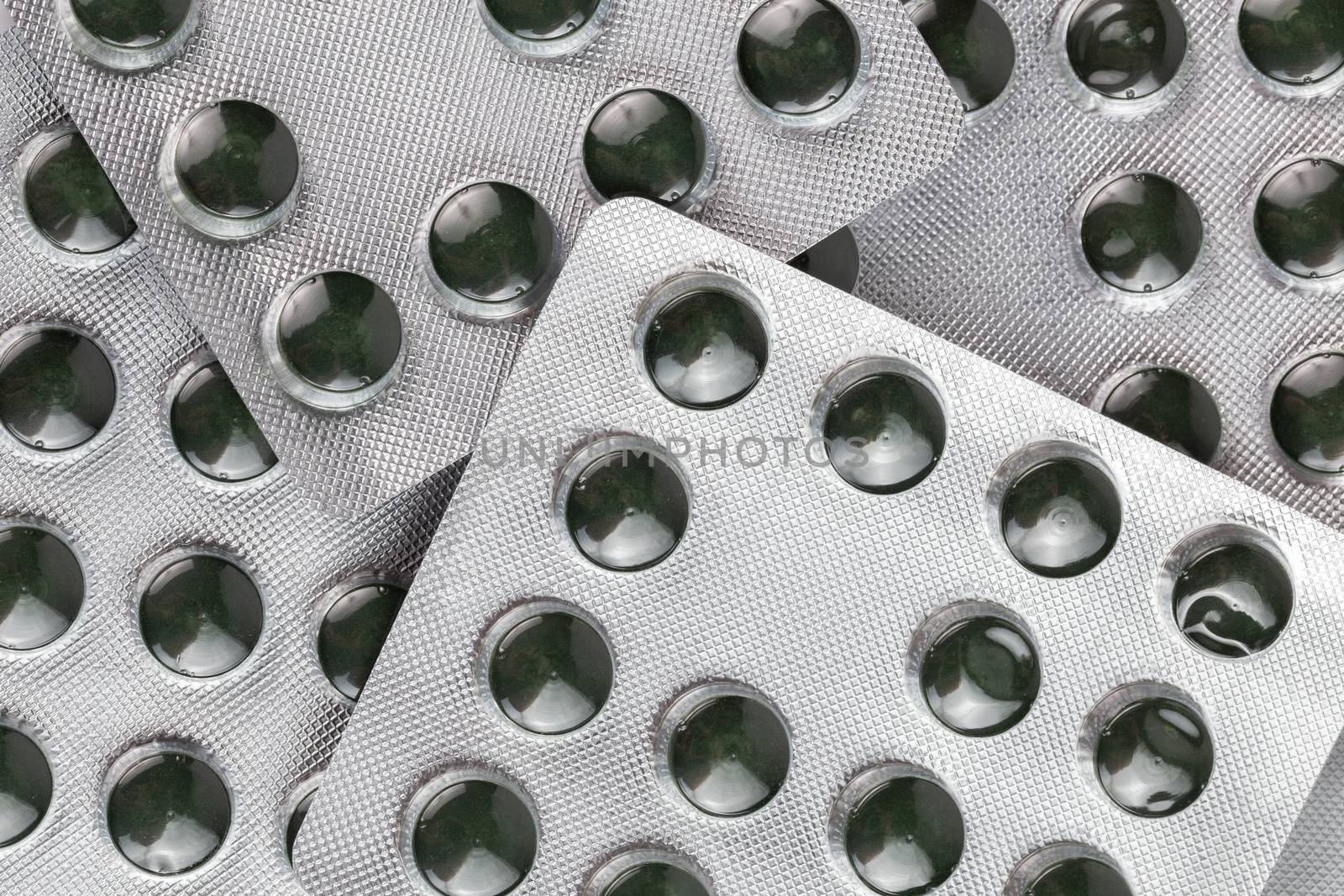 green spirulina pills in medical blister packs close-up with directly above perspective by z1b