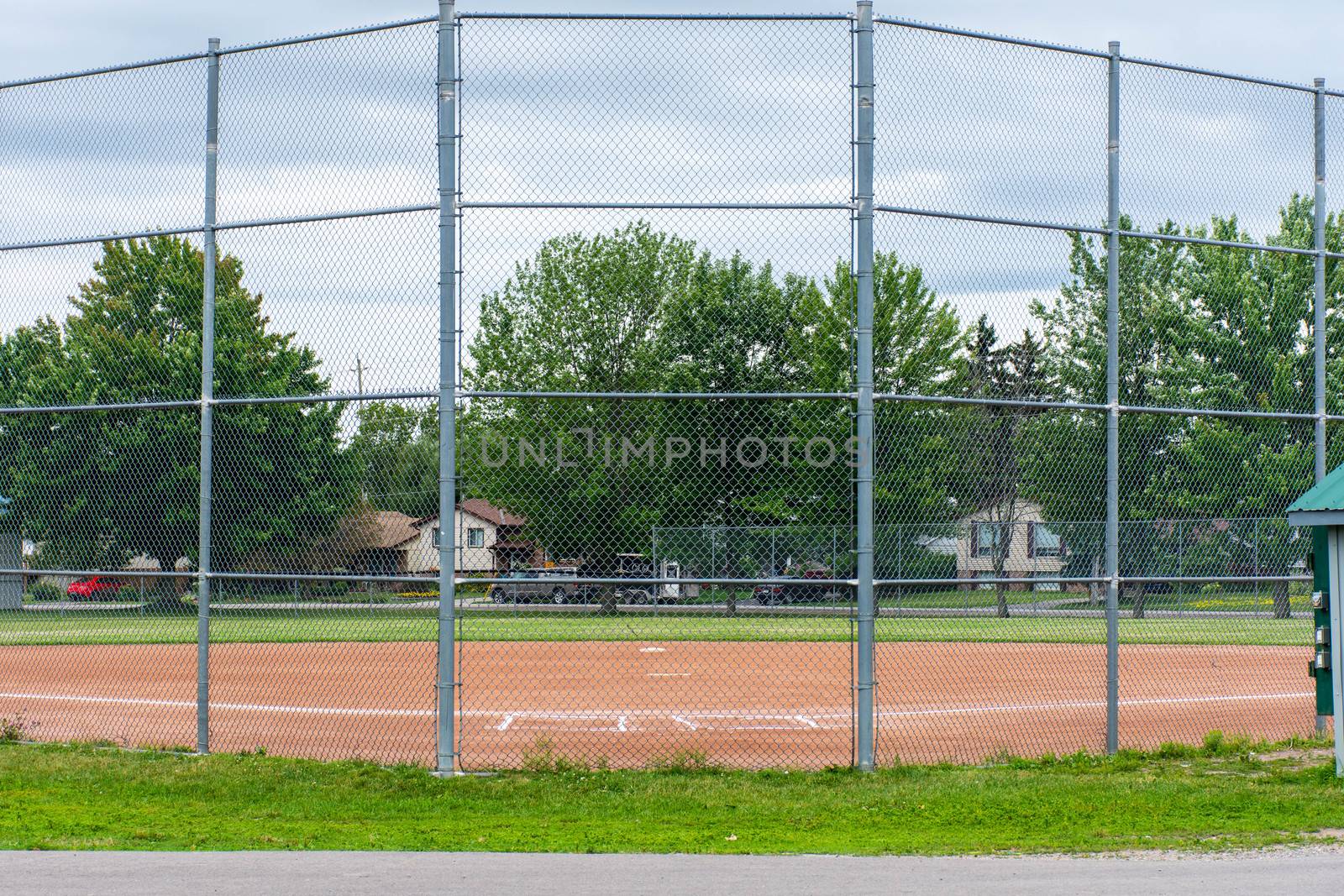 Baseball or softball diamond through a fence in  park in a small by kingmaphotos