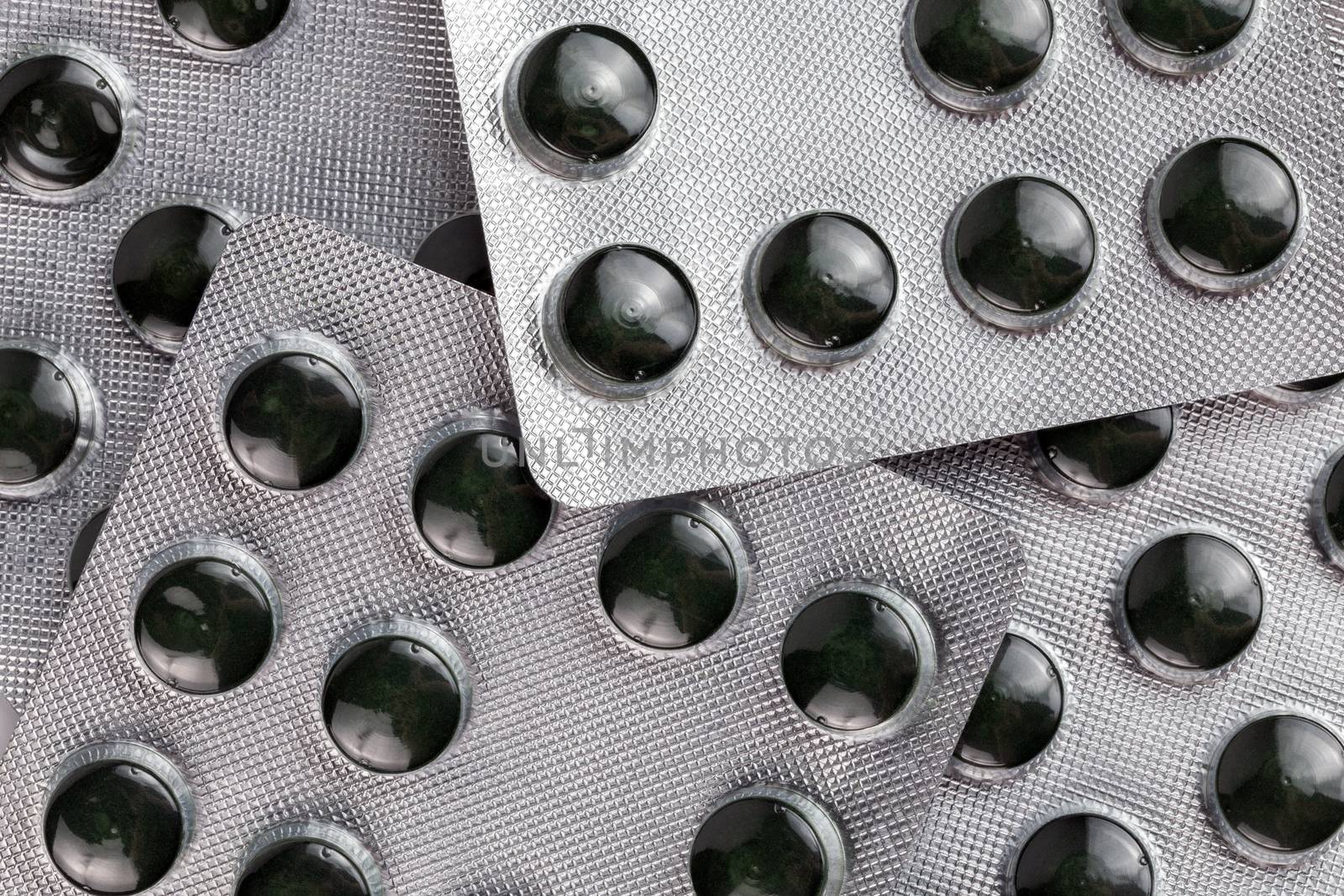raw green compact spirulina powder pills in medical blister packs close-up with selective focus and background blur