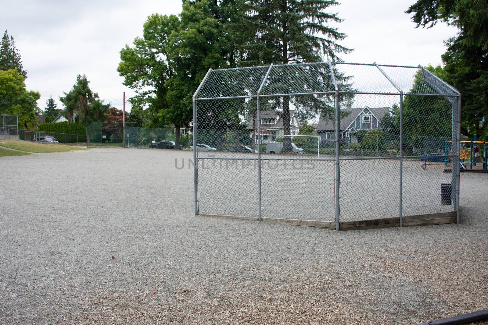 Baseball or softball diamond through a fence in  park in a small by kingmaphotos