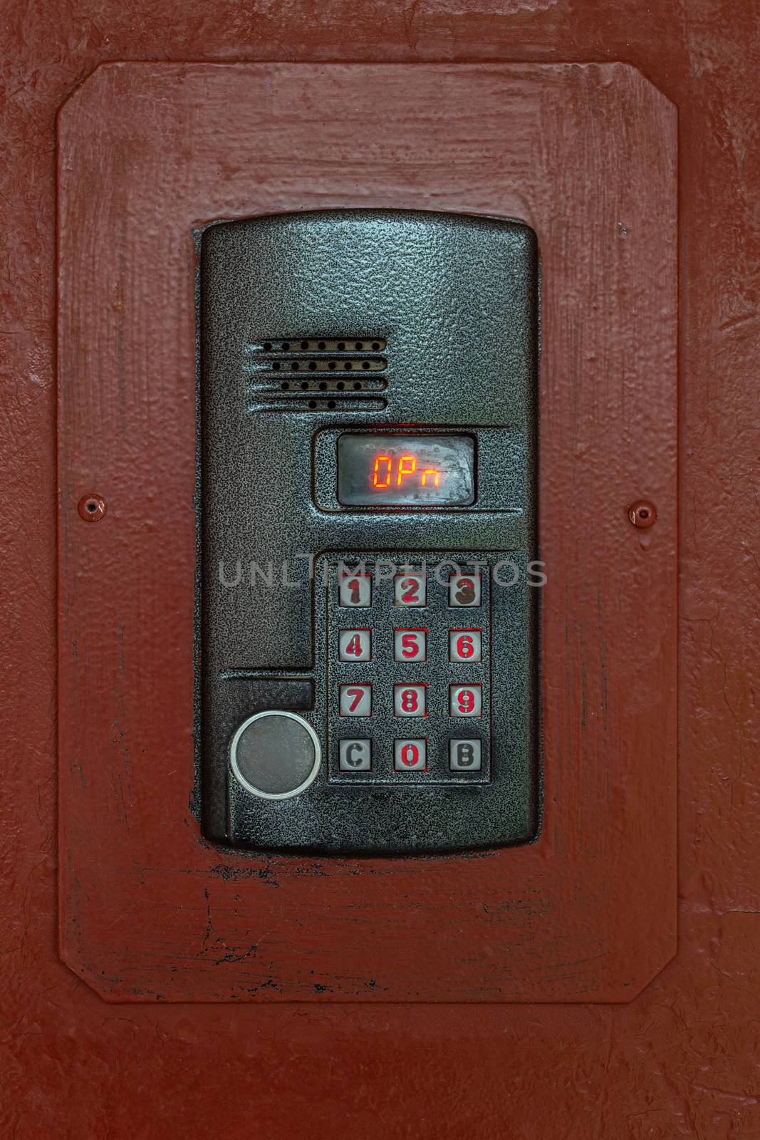 an intercom on old painted brown steel surface with a keypad, digital display and rfid sensor for calling close-up.