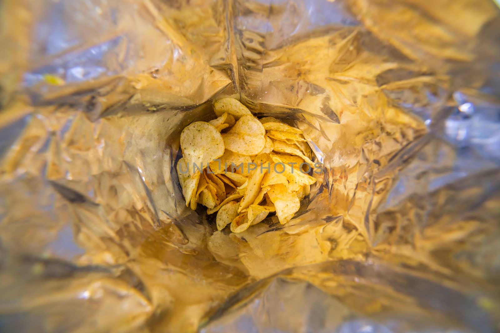 close-up view inside of a big silver bag of potato chips with selective focus and blur