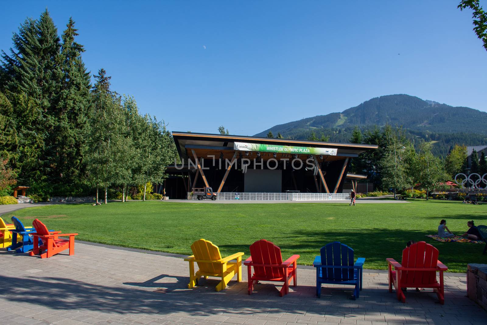 "Whistler, British Columbia/Canada - 8/7/2019: Whistler Olympics Village from 2010 Winter Games. Open Square in summer looking at mountain range and stage."