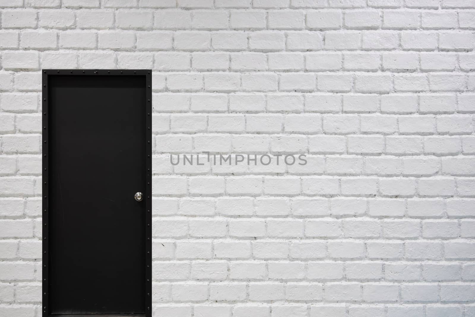 white brick wall background with black door by Charnsitr