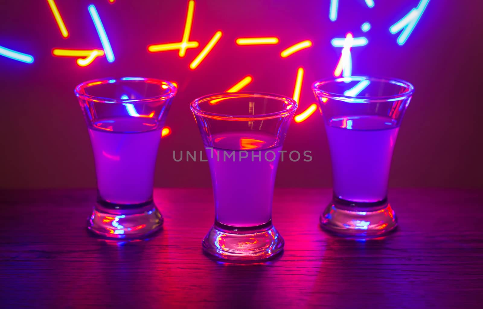 Three drinks at the party. Three shots with cocktails at the bar. Liquor, vodka, fresh. Shining on a colored background. Night club, after the party.