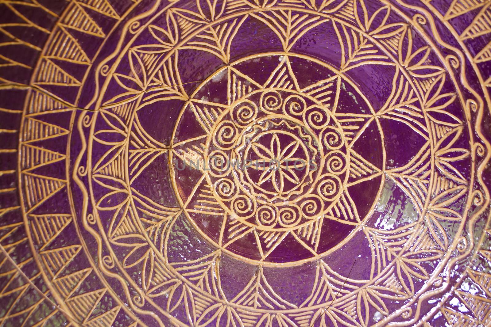 Traditional pattern of tile mandala bowl pottery. Golden and purple colors, close up