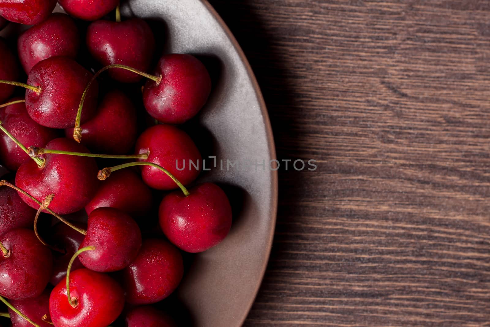 Cherries on a plate, on a wooden background. Summer picnic, harvest, treats. Food for vegetarians and vegans. Proper nutrition, healthy lifestyle, diet, diabetes