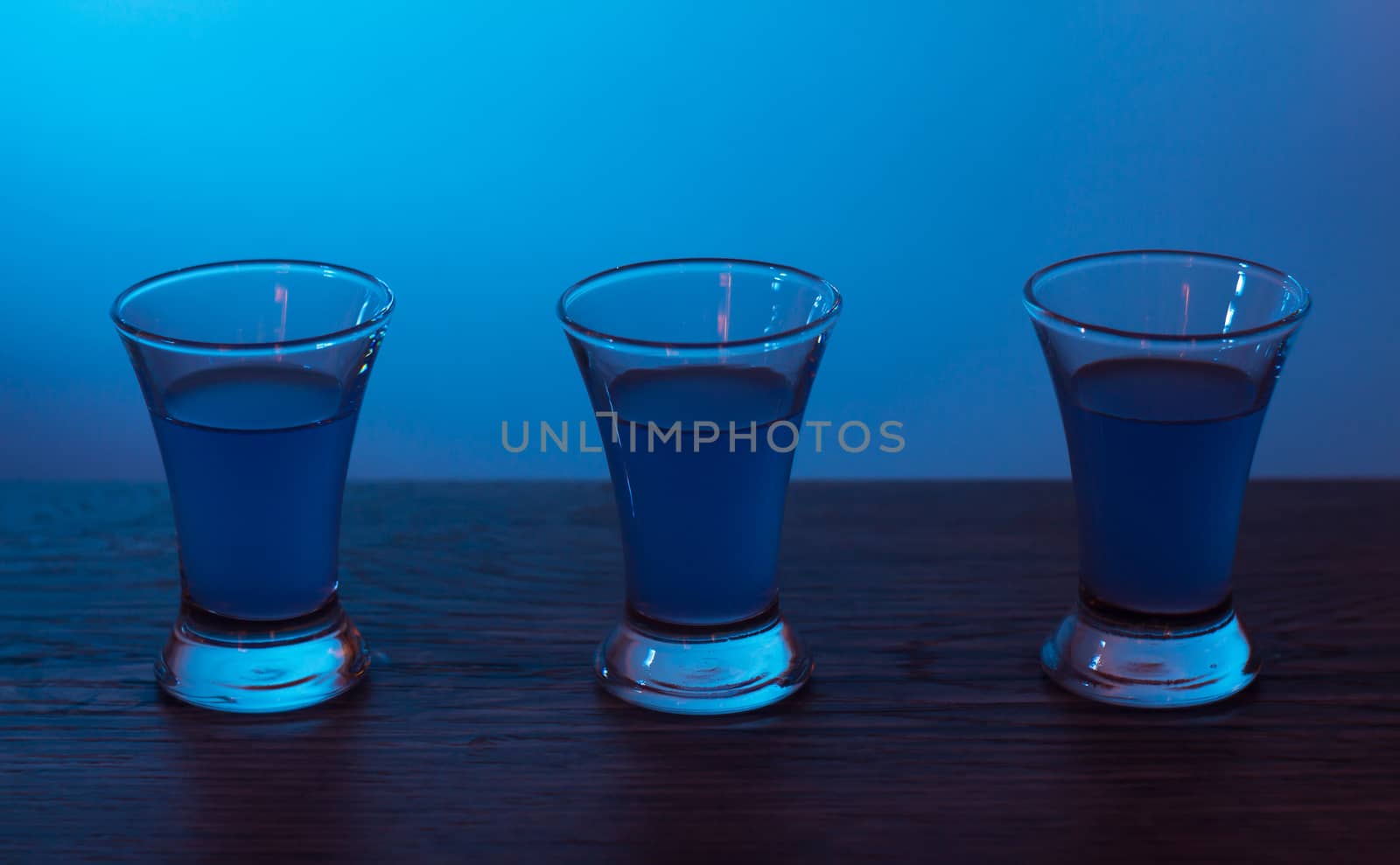 Three drinks at the party. Three shots with cocktails at the bar. Liquor, vodka, fresh. Shining on a colored background. Night club, after party.