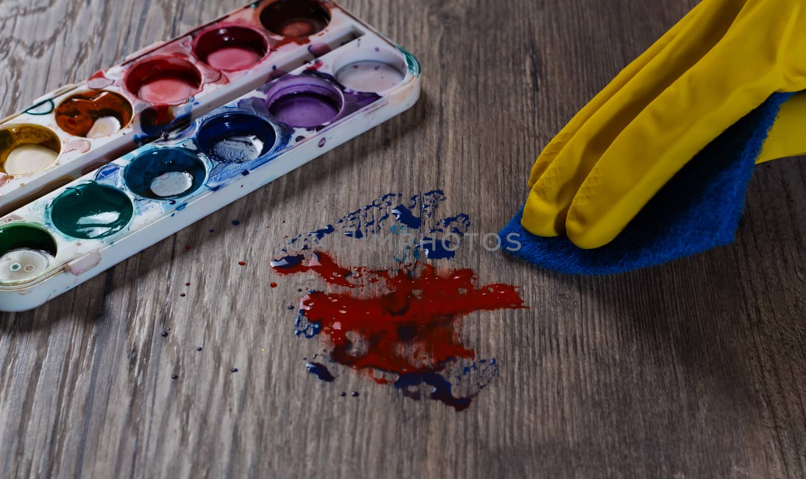 Woman cleans the table stained with paint. A stain from the paint palette. housewife, housework, cleaner, wash,
