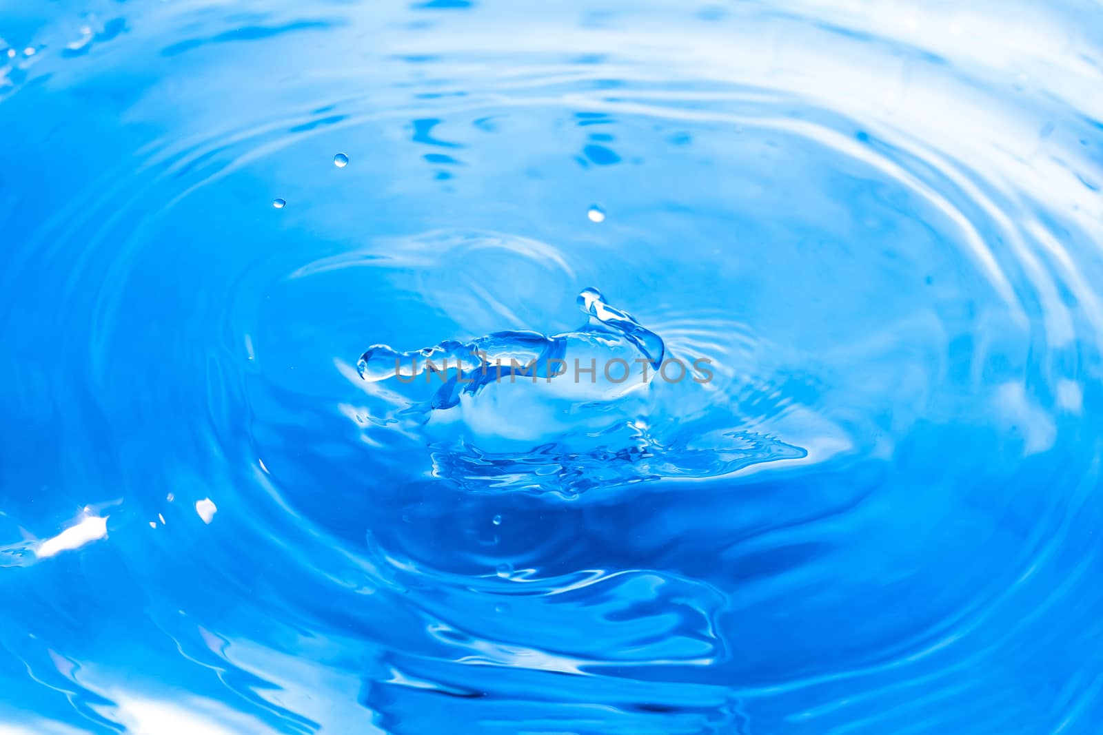 Water drops on blue surface. Water ripple background. Splashes from a drop of water. Raindrops on a blue background. The texture of the water. Aqua, turquoise, macro