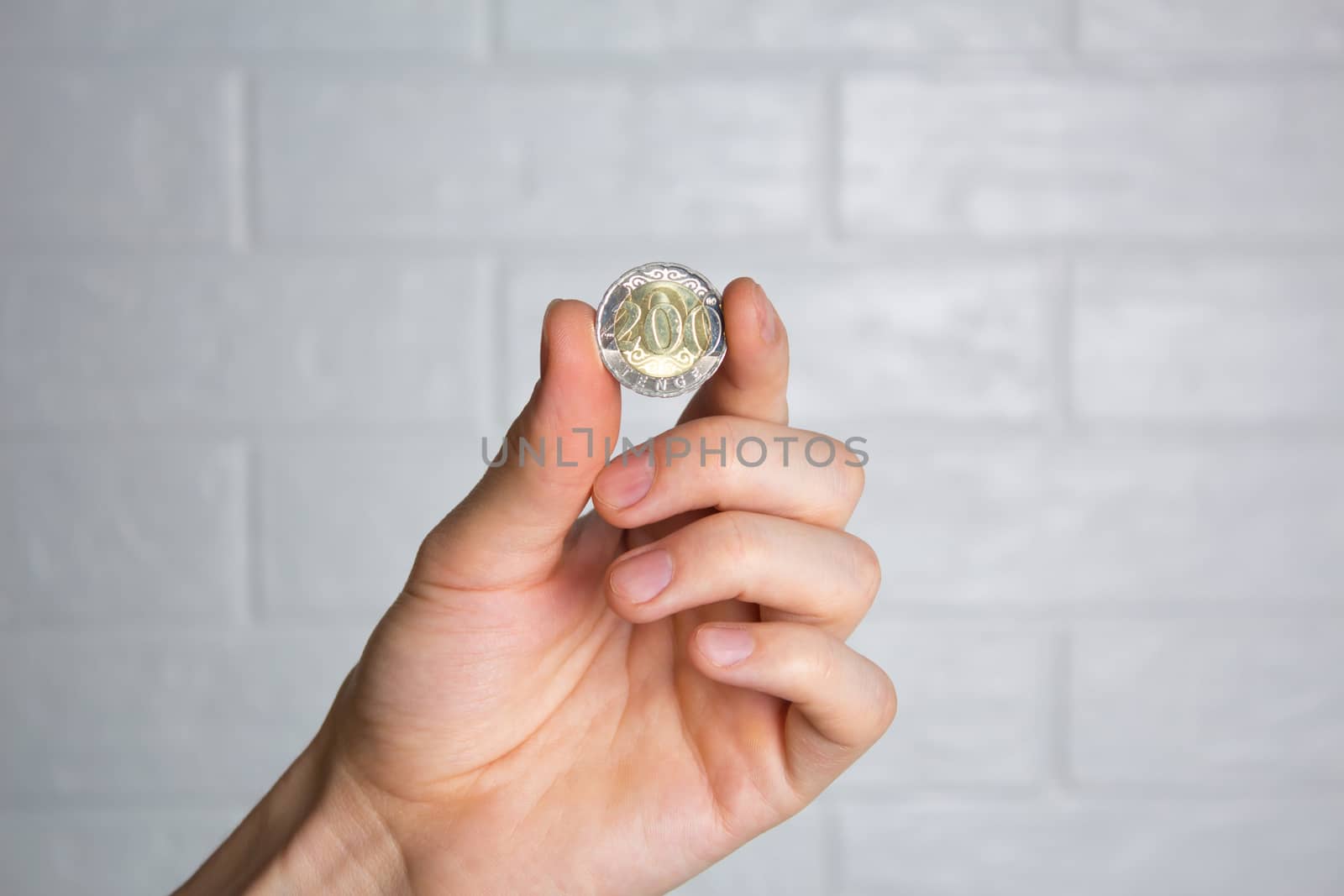 Hold the tenge coin in your hand. Close up. New Kazakhstan coin 200 tenge. Money, Bank, save, spend.