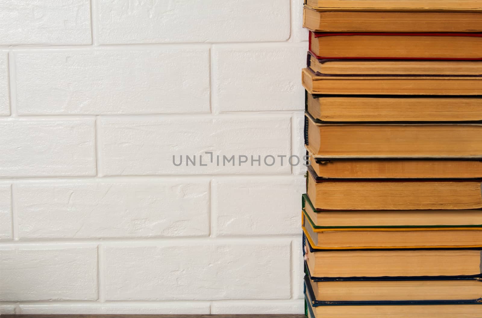 A stack of old books. Bookstore, library, bookshelf. Vintage, retro, antique.  Study, education, school, University. Literature, history, science. Books against a white brick wall. copy space