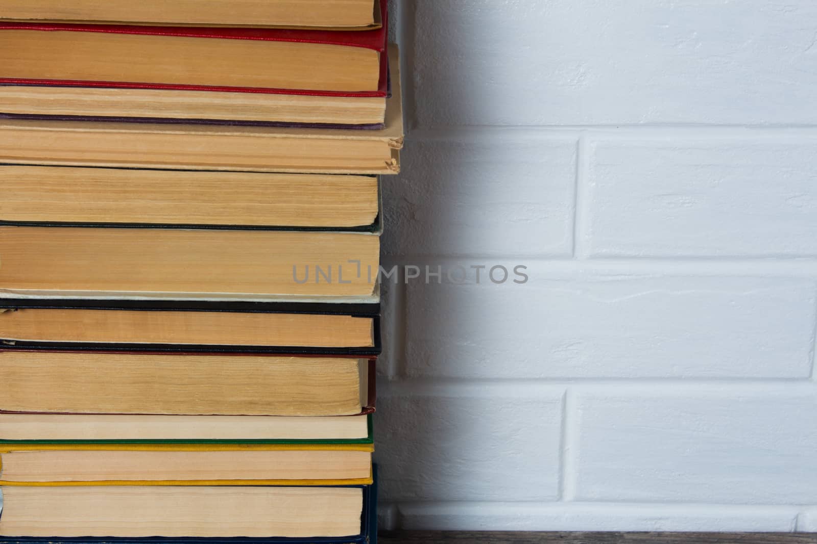 A stack of old books. Bookstore, library, bookshelf. Vintage, retro, antique.  Study, education, school, University. Literature, history, science. Books against a white brick wall. copy space