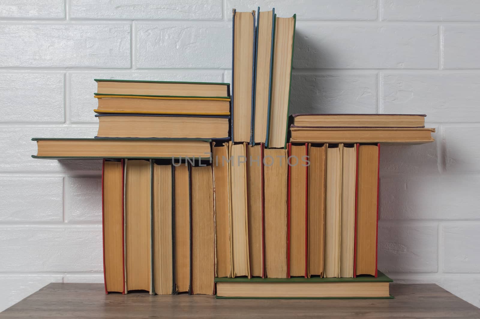 A stack of old books. Bookstore, library, bookshelf. Vintage, retro, antique. Study, education, school, University. Literature, history, science. Books against a white brick wall.
