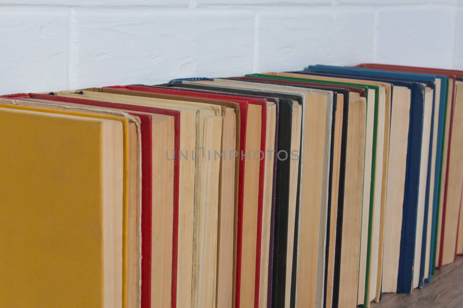 A stack of old books. Bookstore, library, bookshelf. Vintage, retro, antique. Study, education, school, University. Literature, history, science. Books against a white brick wall.